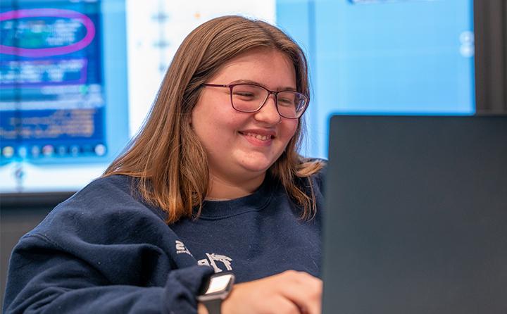Data science student smiling and looking at laptop
